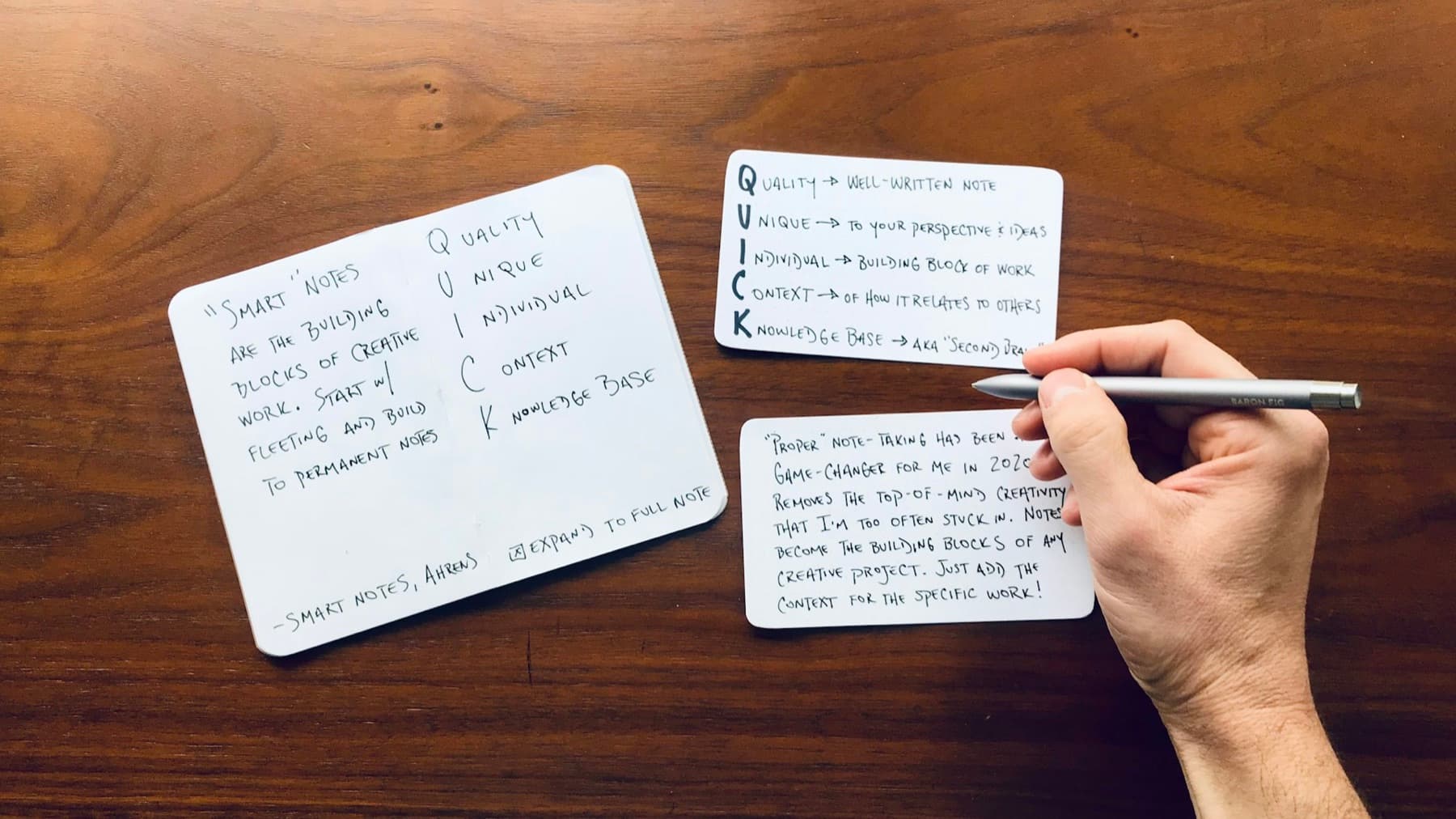 A hand writing on index cards spread across a wooden table